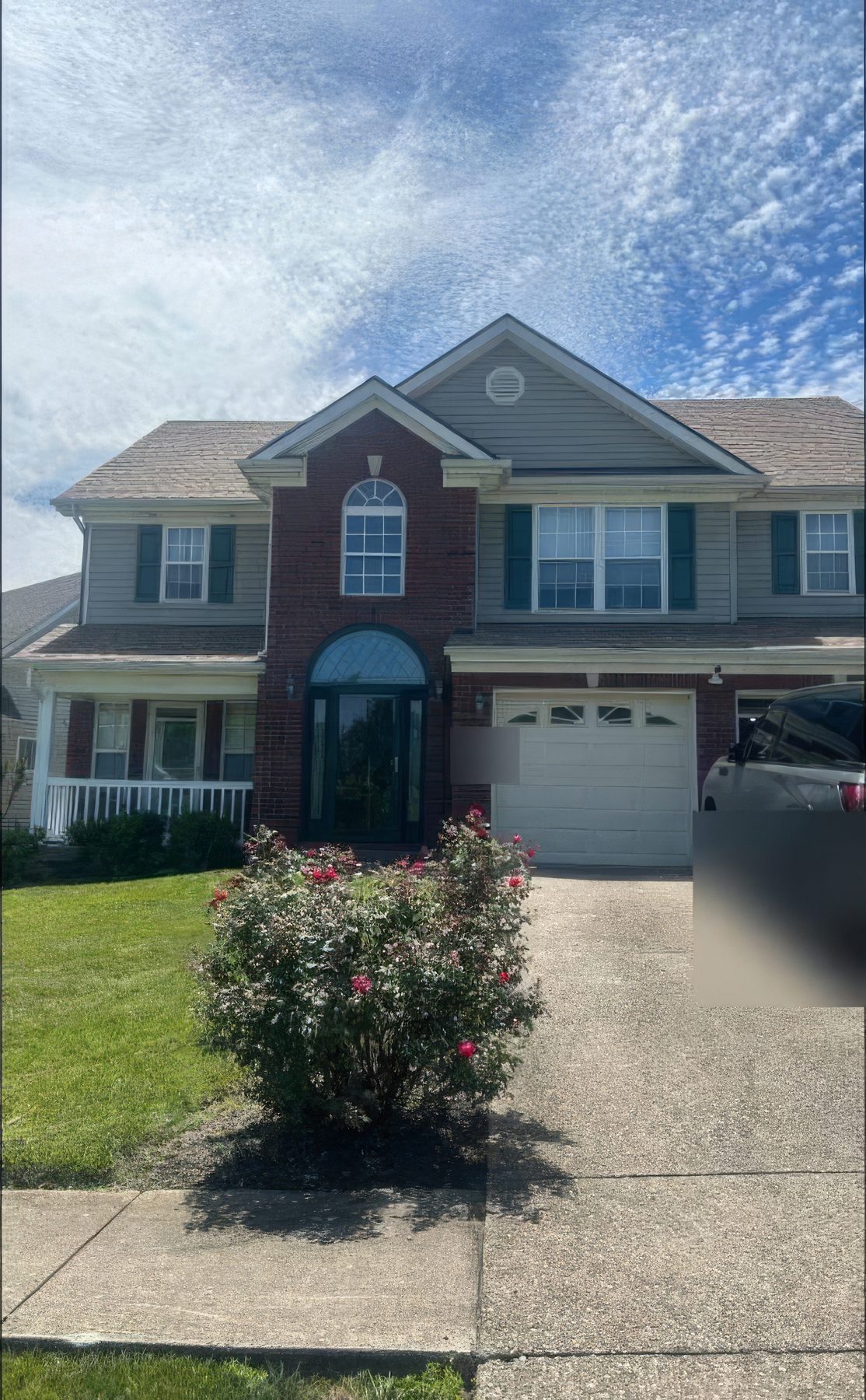 A two story brick and siding house from the street with its new roof on